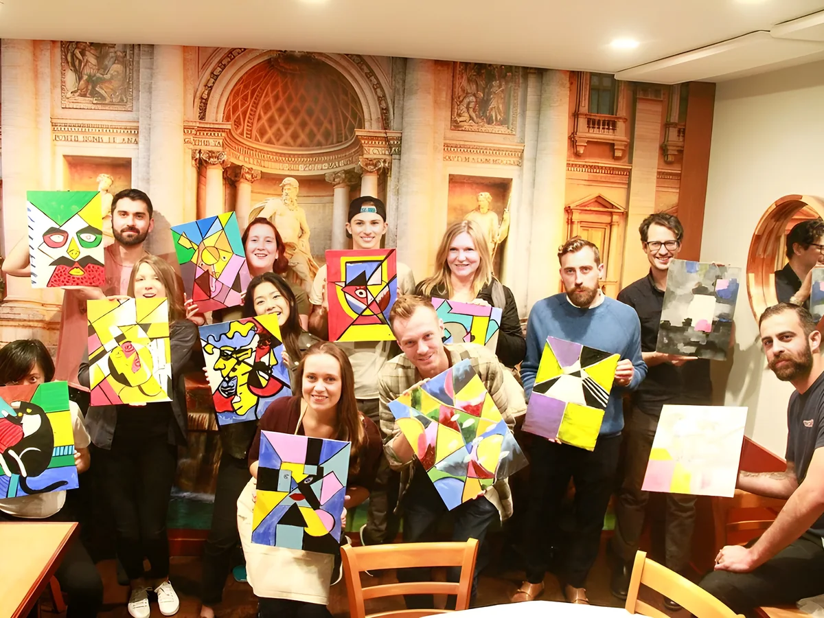 A team holding up the bold abstract paintings they made together