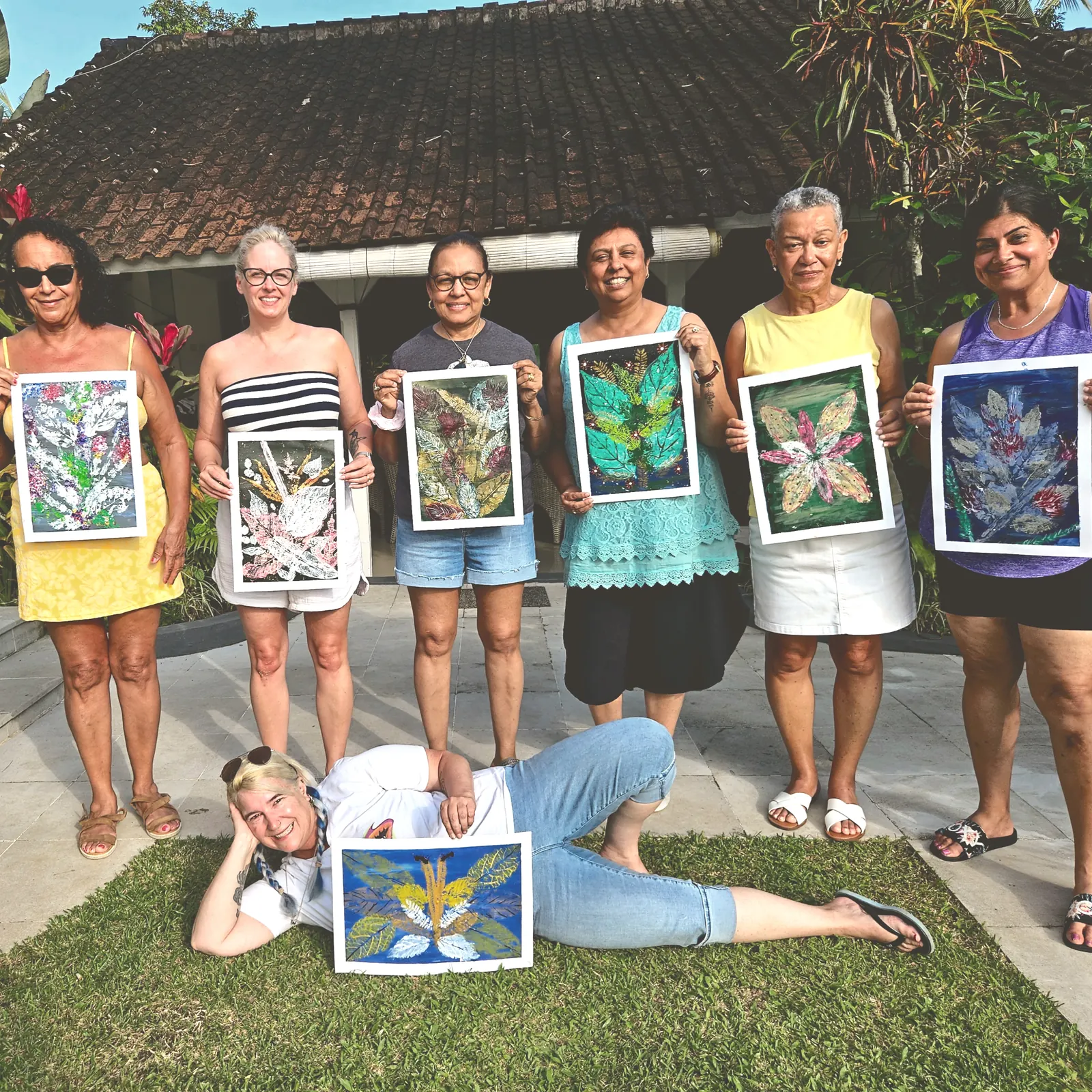 Women at a Bali retreat holding up the leaf prints they made