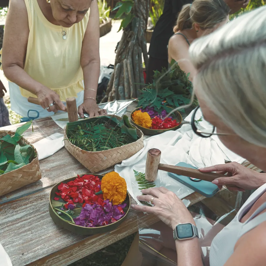 Women hammering flowers and leaves onto fabric to print their colours
