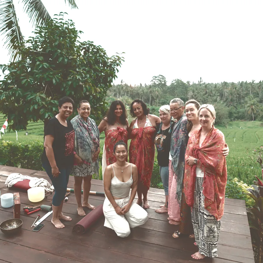 The retreat group together on a wooden deck with singing bowls, rice fields behind