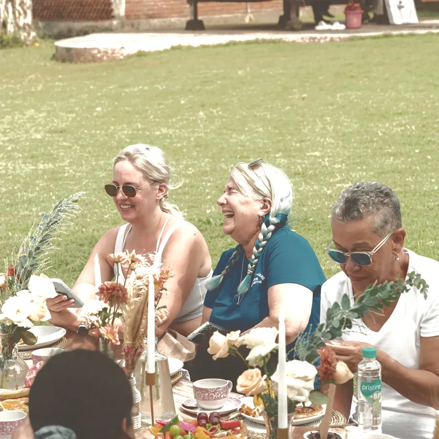 Guests laughing together around a table on the lawn