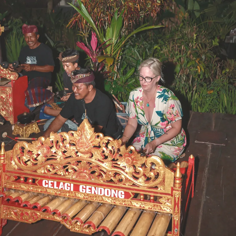 A guest learning to play a gamelan with local musicians