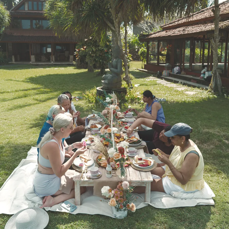A long picnic table set on the lawn, women sharing breakfast