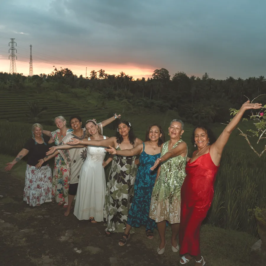The retreat group laughing with arms open in a field at sunset
