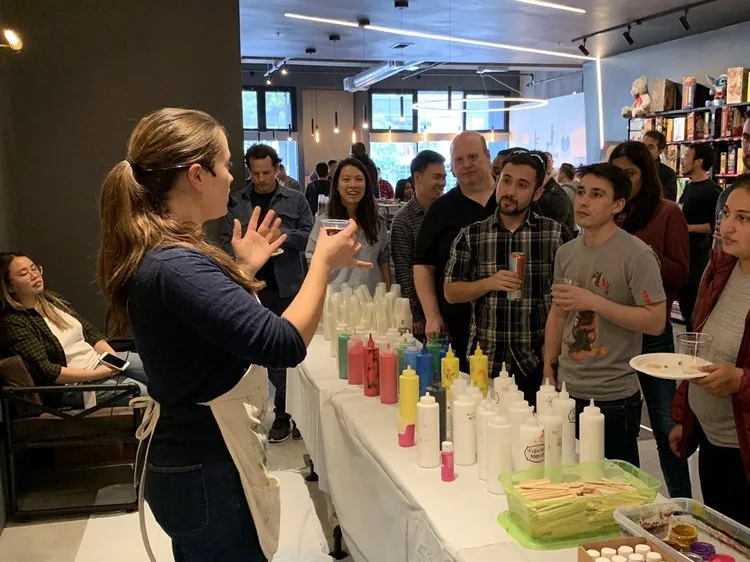 Ana teaching an acrylic pouring workshop to a company team in their office