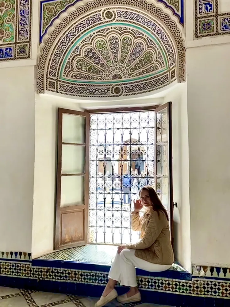 Ana sitting in a tiled window seat beneath a carved and painted arch